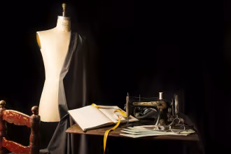 Eine N&auml;hmaschine mit einem wei&szlig;en K&ouml;rper und einem goldenen Kopf, auf einem Holztisch mit einem wei&szlig;en Buch und einem Paar Schneidemesser.