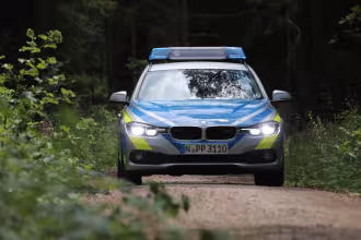 Polizeifahrzeug steht auf einem Waldweg
